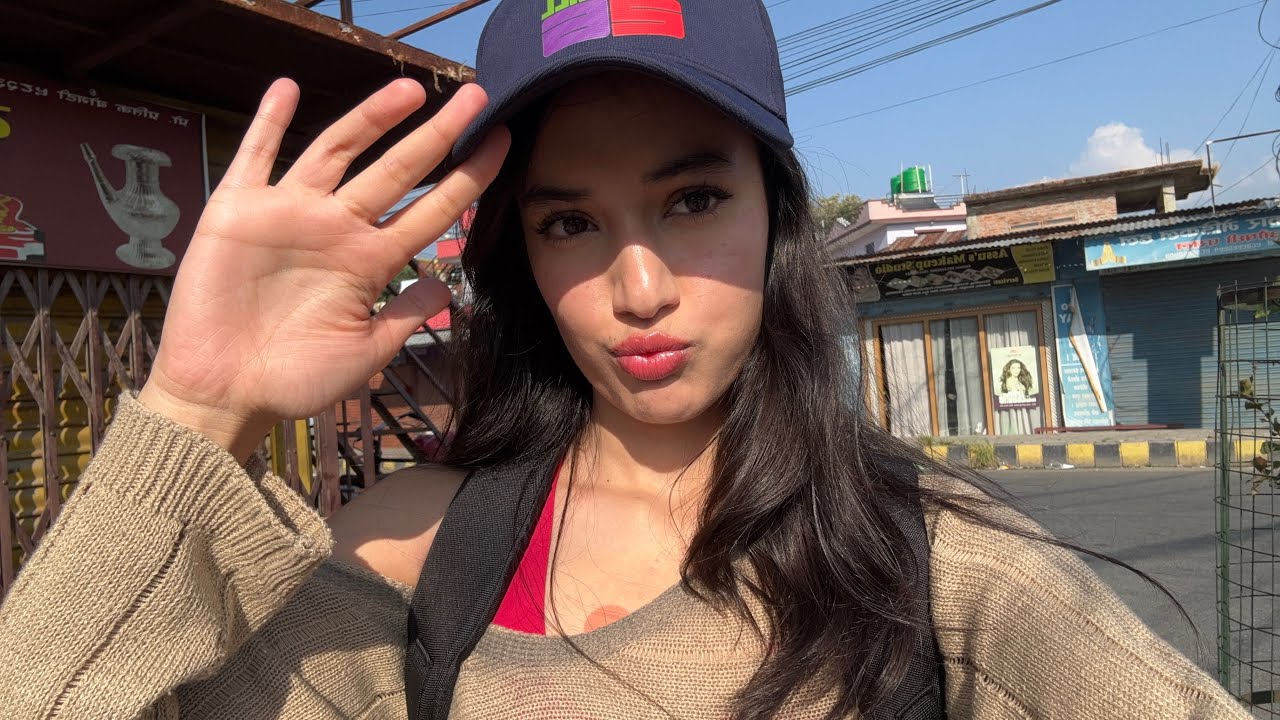 Claypie in a cap, waving at the camera on a sunny Kathmandu street
